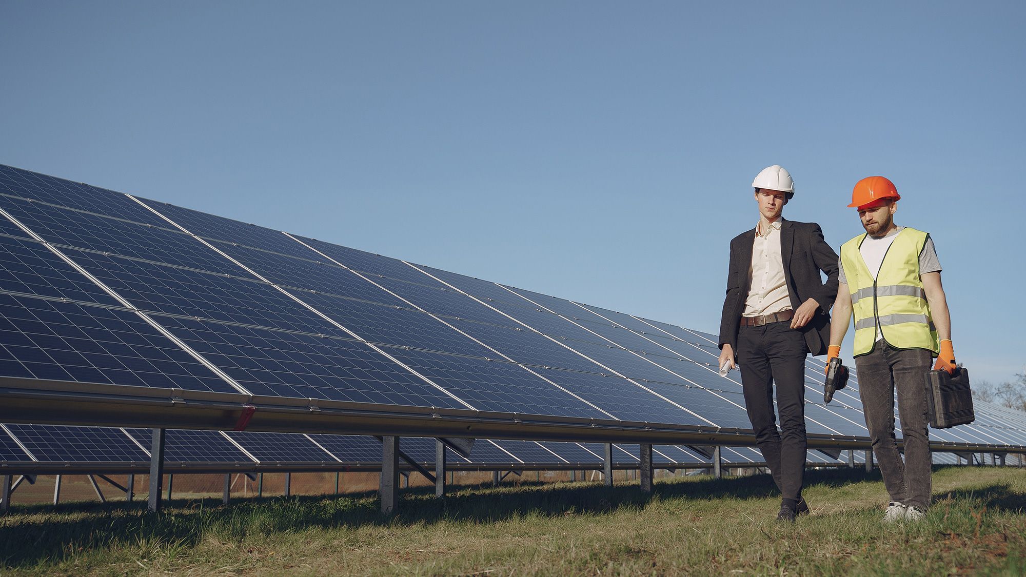 Solar farm engineer talking to a business owner with solar panels in the background